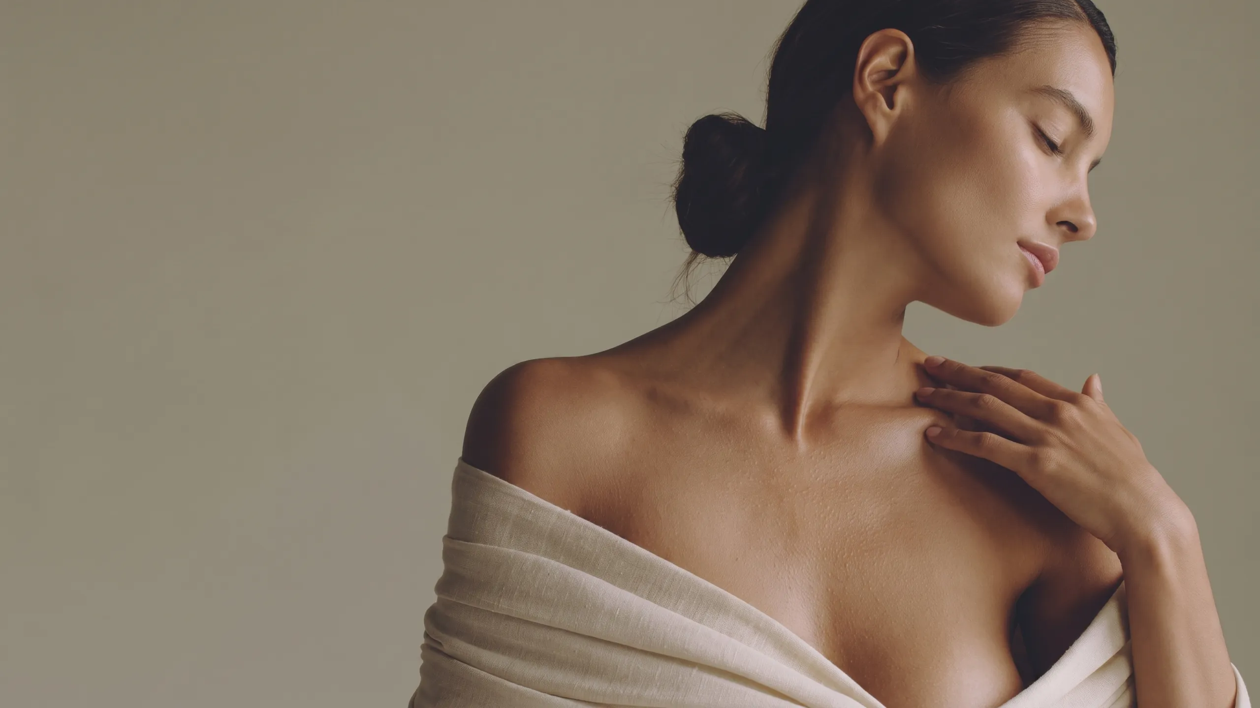 Bare shoulders and a hand at the collarbone, eyes closed